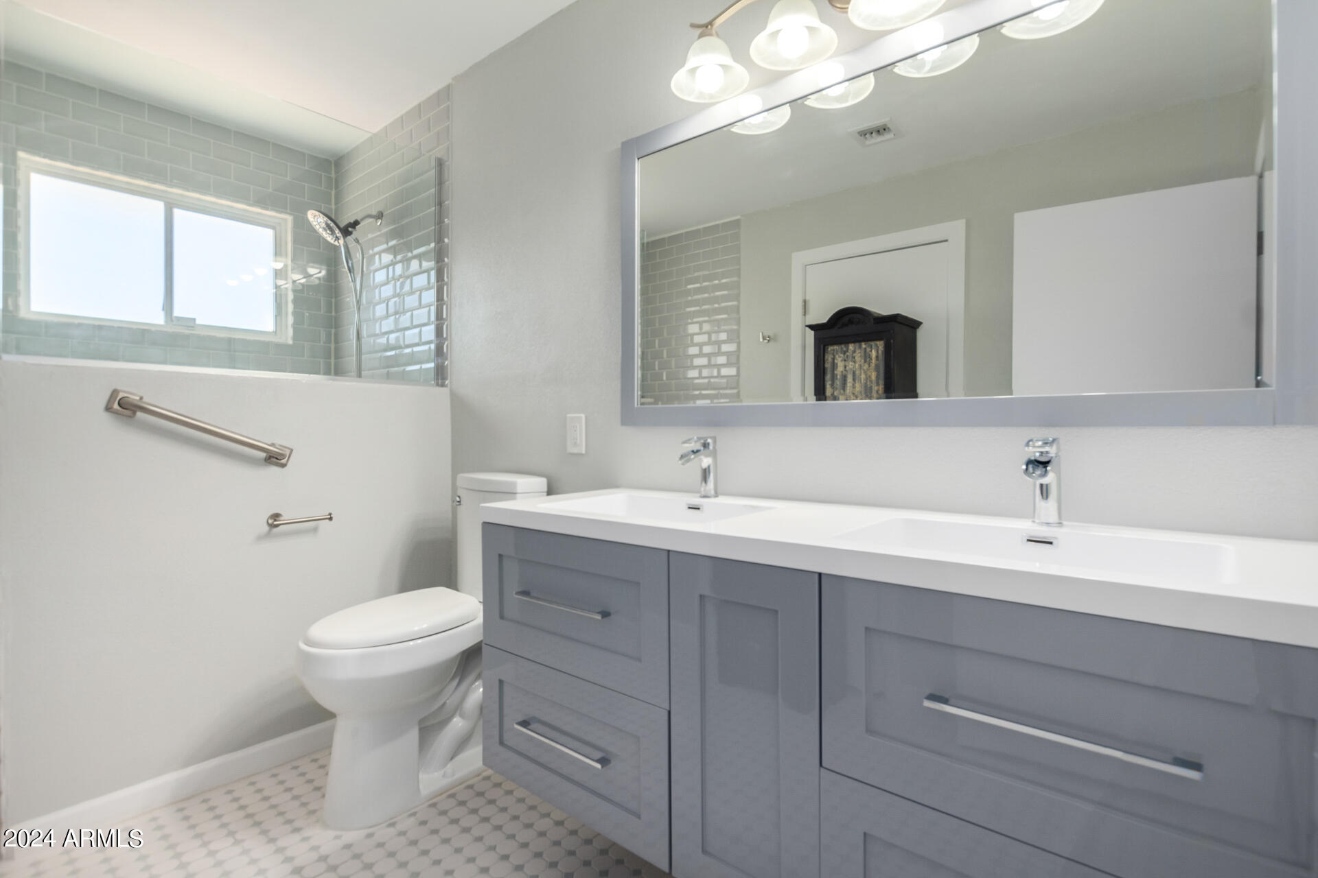 3216 West Hearn Road Phoenix, AZ 85053 - Photo 24 of 32 a bathroom with a toilet a sink a mirror and a window
