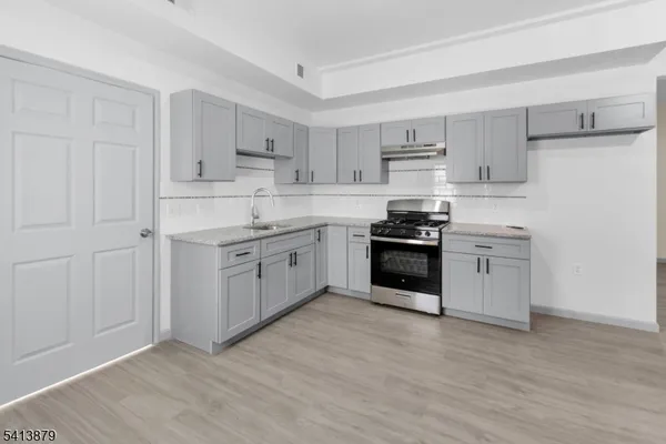 a kitchen with stainless steel appliances granite countertop a stove top oven a sink and white cabinets
