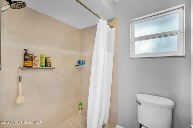a white toilet sitting next to a shower