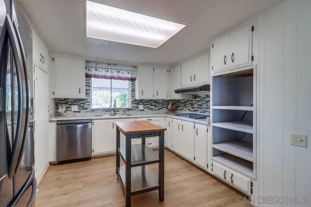 18218 Paradise Mountain Road, Unit 129 Valley Center, CA 92082 - Photo 16 of 58 a kitchen with granite countertop stainless steel appliances a stove and a refrigerator