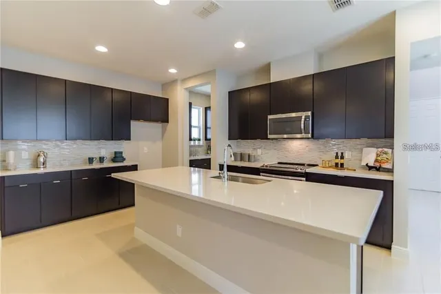 a large kitchen with stainless steel appliances wooden cabinets a stove a sink and a microwave