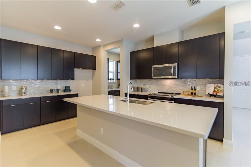 7241 Sunny Meadow Windermere, FL 34786 - Photo 2 of 14 a large kitchen with stainless steel appliances wooden cabinets a stove a sink and a microwave