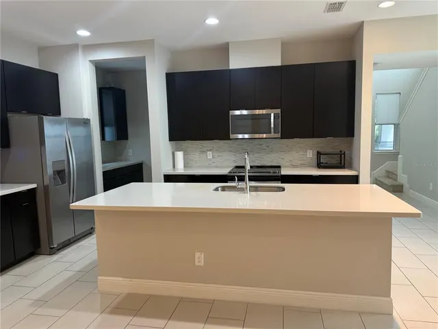 a kitchen with kitchen island a refrigerator sink and stove
