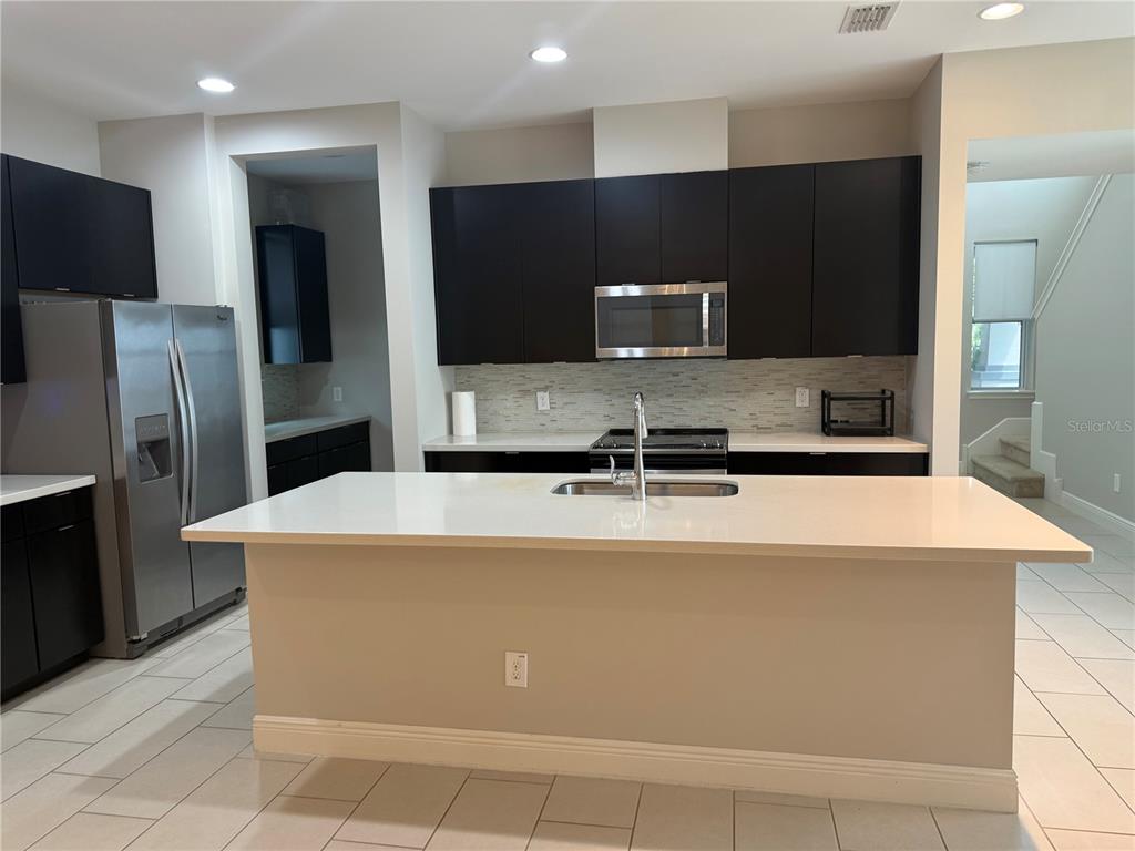 7241 Sunny Meadow Windermere, FL 34786 - Photo 3 of 14 a kitchen with kitchen island a refrigerator sink and stove