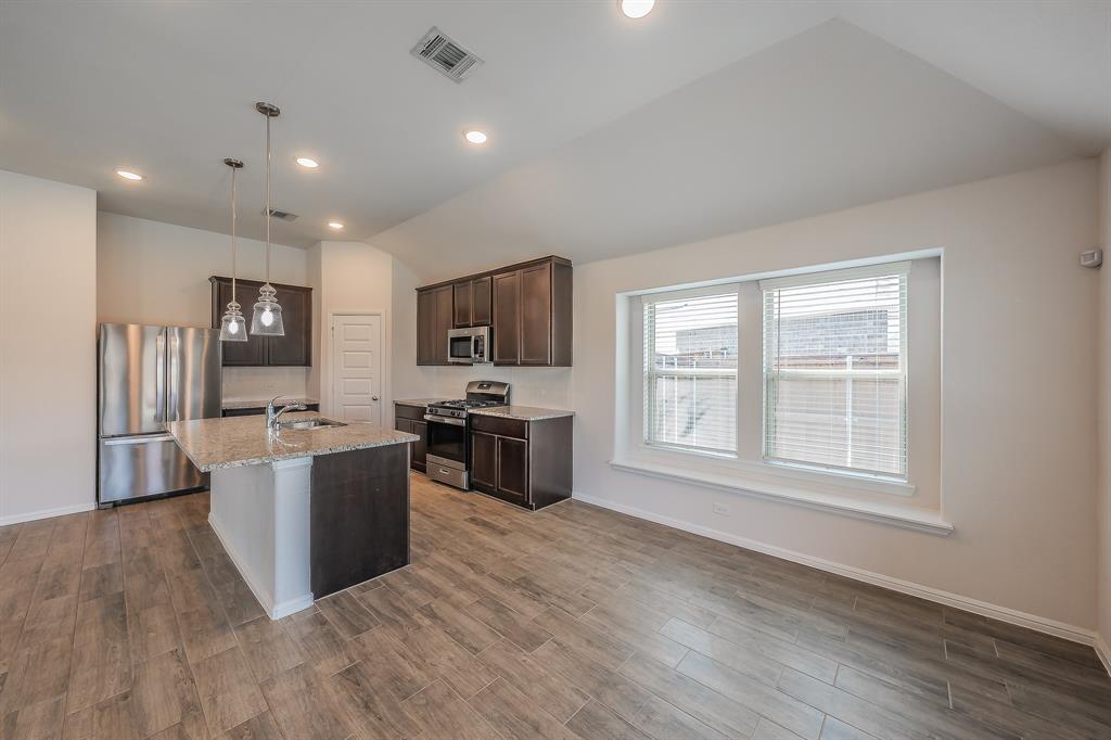 2727 Rambling Road Celina, TX 75009 - Photo 18 of 40 a kitchen with stainless steel appliances a stove top oven a sink dishwasher a refrigerator and a refrigerator with wooden floor