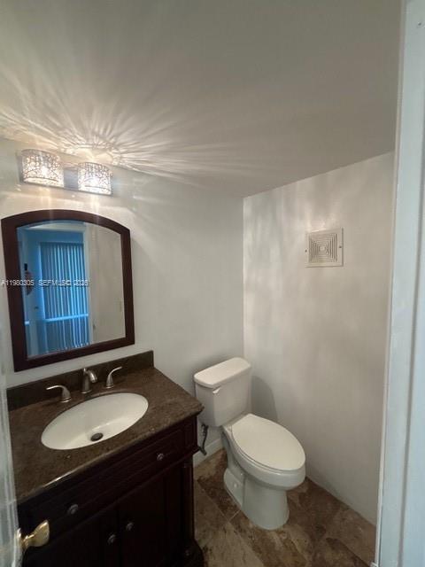 305 Preston F, Unit H Boca Raton, FL 33434 - Photo 9 of 17 a bathroom with a granite countertop toilet sink and mirror
