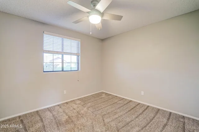 an empty room with a window and ceiling fan