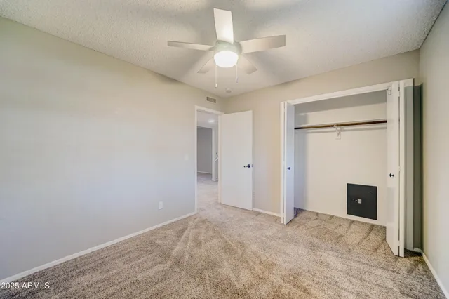 an empty room with closet and a ceiling fan