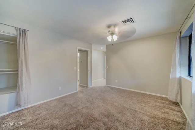 a view of an empty room with a chandelier fan