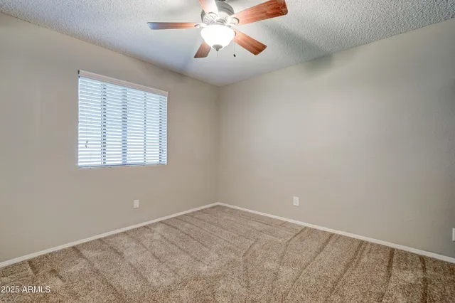 an empty room with a window and a fan