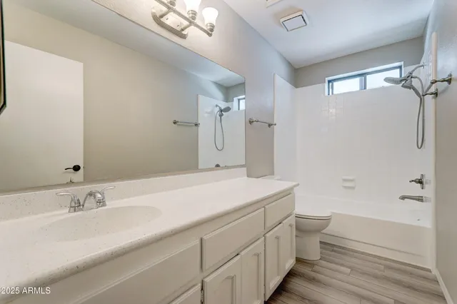 a bathroom with a granite countertop sink a toilet and shower