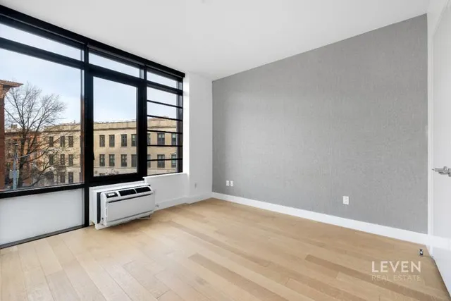 a spacious bedroom with a bed and glass top table