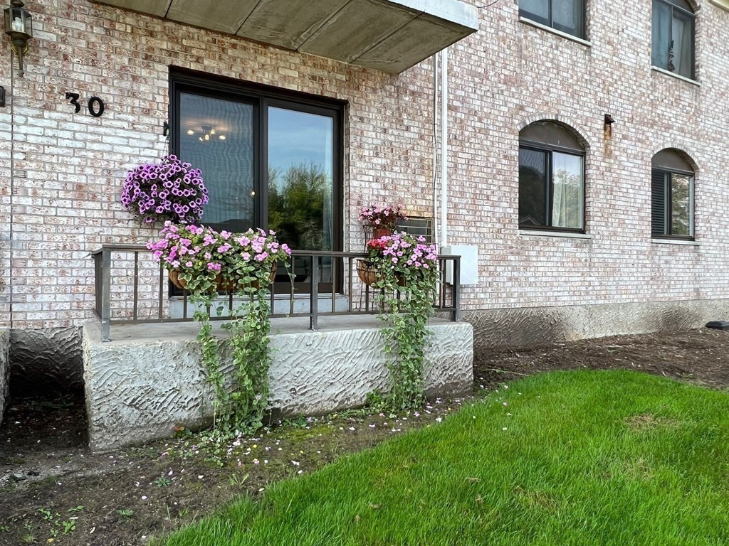 30 High Street, Unit 101 Dedham, MA 02026 - Photo 2 of 36 a front view of a house with a garden