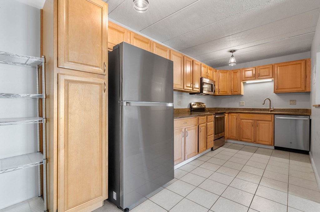 30 High Street, Unit 101 Dedham, MA 02026 - Photo 31 of 36 a kitchen with cabinets stainless steel appliances and a window