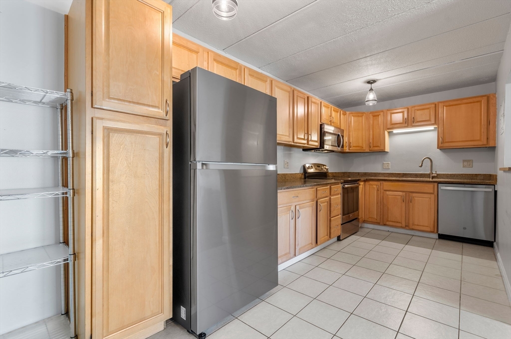 30 High Street, Unit 101 Dedham, MA 02026 - Photo 8 of 36 a kitchen with cabinets stainless steel appliances and a window