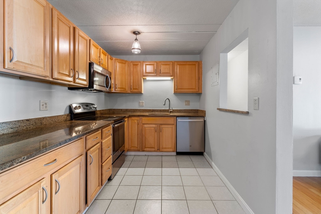 30 High Street, Unit 101 Dedham, MA 02026 - Photo 9 of 36 a kitchen with stainless steel appliances granite countertop a sink and cabinets