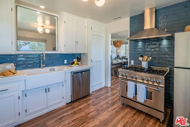 a kitchen with stainless steel appliances granite countertop a stove a sink and white cabinets