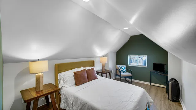 a bedroom with a bed and a flat tv screen on dresser