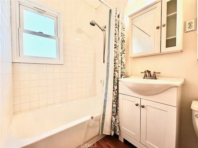 an empty room with wooden floor window and ceiling fan