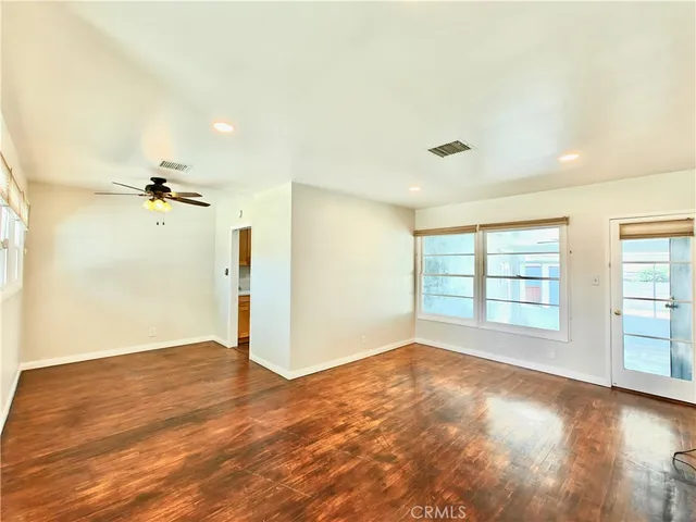 an empty room with wooden floor and windows