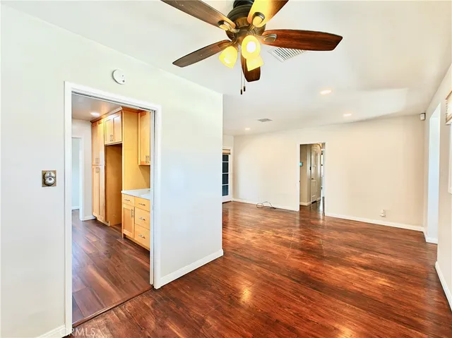an empty room with wooden floor cabinet and windows