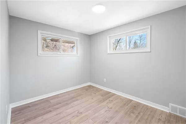 an empty room with wooden floor and window