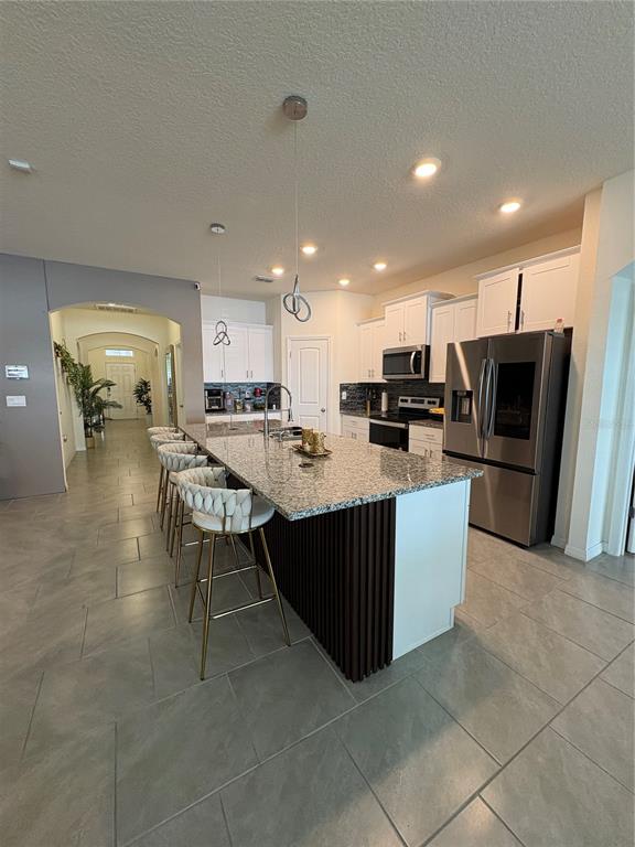 1948 Rankin Street Kissimmee, FL 34744 - Photo 12 of 37 a kitchen with stainless steel appliances kitchen island granite countertop a refrigerator a stove a sink a oven with a dining table and chairs