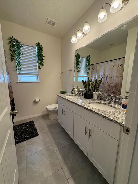 1948 Rankin Street Kissimmee, FL 34744 - Photo 8 of 37 a spacious bathroom with a granite countertop sink a toilet a mirror and vanity