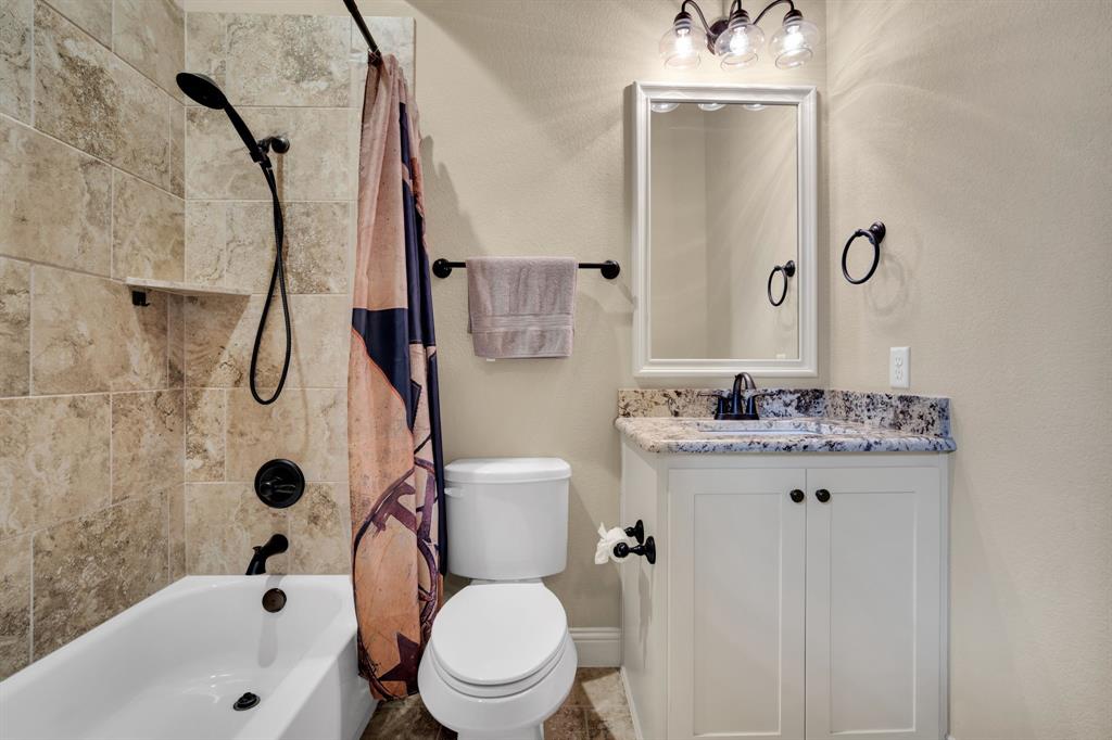 409 George Hopper Road Midlothian, TX 76065 - Photo 19 of 26 a bathroom with a granite countertop toilet a sink and a bathtub