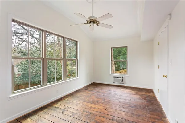 a view of an empty room with wooden floor and a window