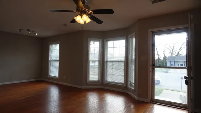 a view of empty room with wooden floor and fan
