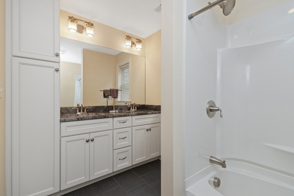 141 Ash Street, Unit 1 Waltham, MA 02453 - Photo 23 of 31 a bathroom with a granite countertop sink a mirror and a bathtub