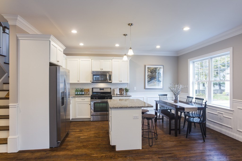 141 Ash Street, Unit 1 Waltham, MA 02453 - Photo 4 of 31 a kitchen with stainless steel appliances granite countertop a stove a refrigerator a sink a dining table and chairs with wooden floor