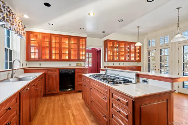 a kitchen with stainless steel appliances a stove a sink dishwasher and white cabinets with wooden floor