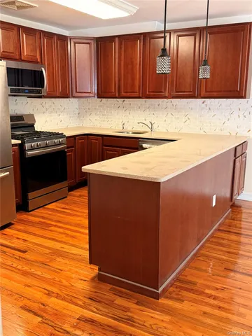 a kitchen with stainless steel appliances kitchen island granite countertop wooden cabinets a stove and a sink