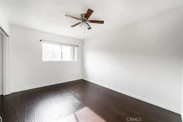 an empty room with wooden floor fan and windows
