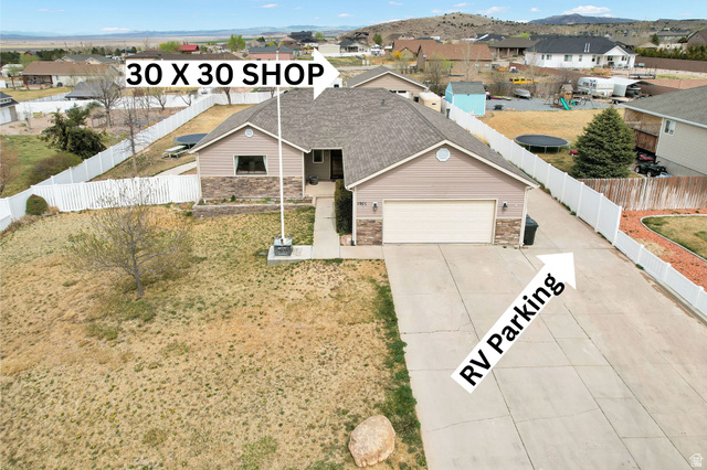 View of front facade featuring a residential view, driveway, an attached garage, and stone siding