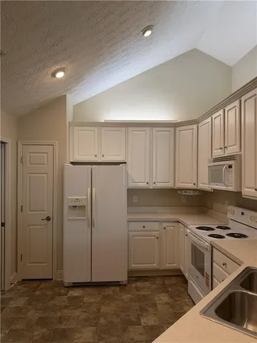 a kitchen with white cabinets and white appliances