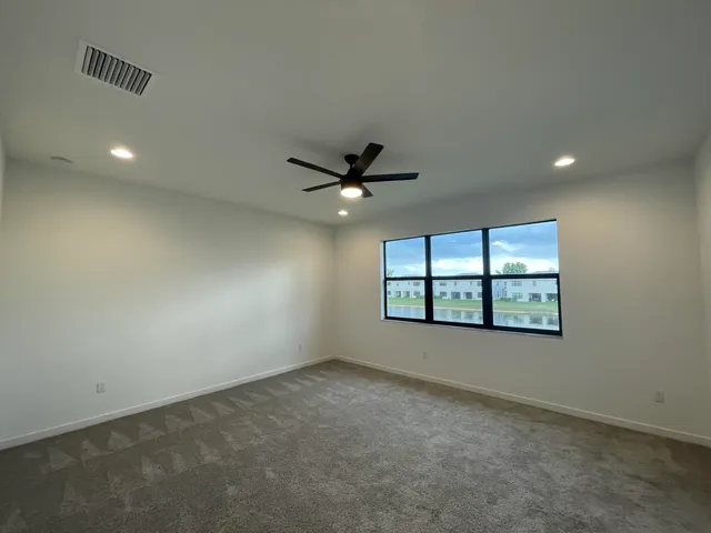 an empty room with a ceiling fan and window
