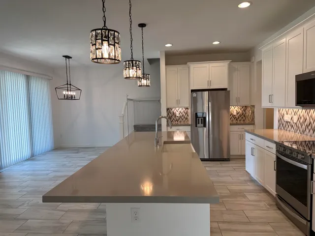 a kitchen with stainless steel appliances granite countertop a sink a oven a refrigerator and a granite counter tops with white cabinets