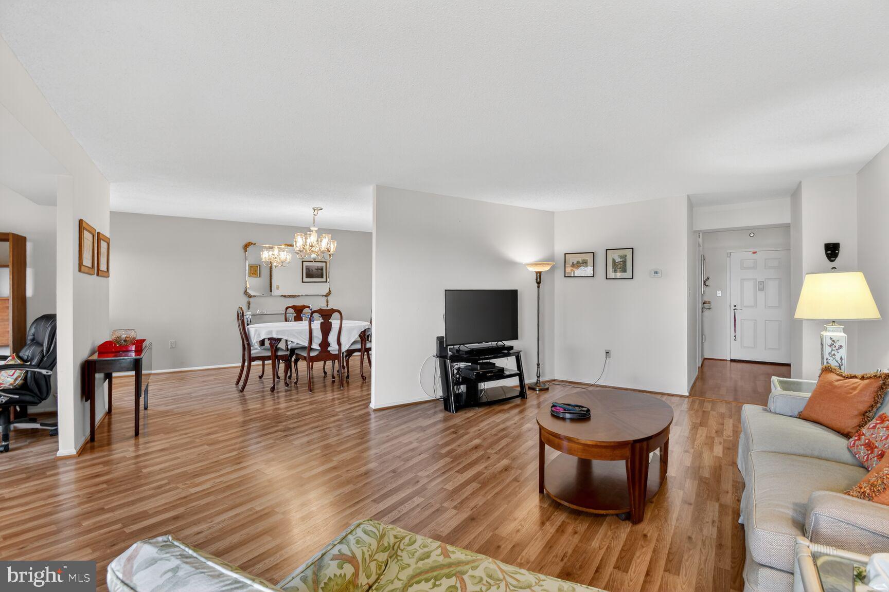 15115 Interlachen Drive, Unit 3904 Silver Spring, MD 20906 - Photo 15 of 43 a living room with furniture a dining table and a flat screen tv with wooden floor
