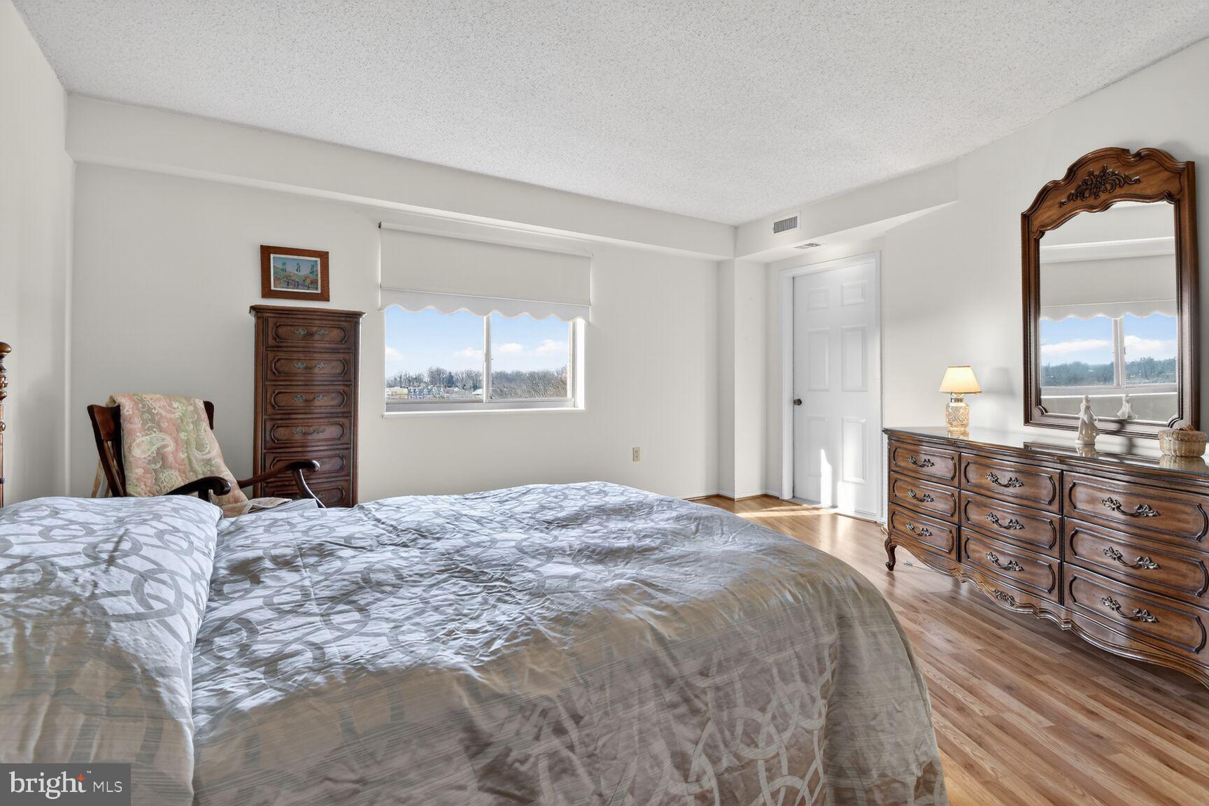 15115 Interlachen Drive, Unit 3904 Silver Spring, MD 20906 - Photo 21 of 43 a large bedroom with a bed and wooden floor