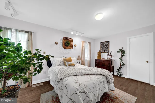 a bedroom with a bed and a potted plant on the dresser