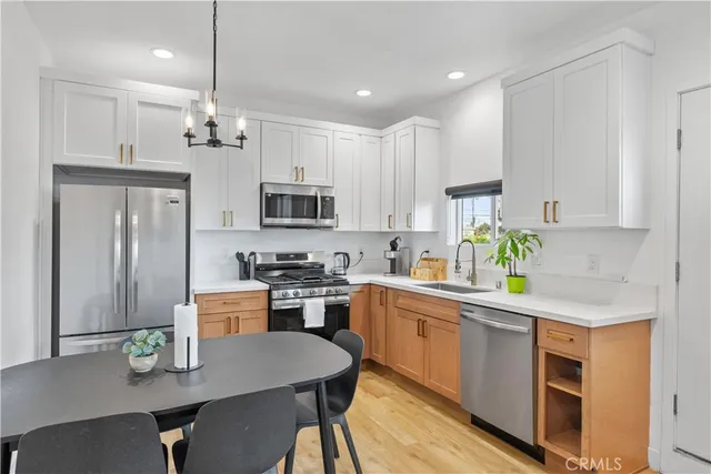 a kitchen with stainless steel appliances kitchen island granite countertop a sink a stove a refrigerator cabinets and chairs