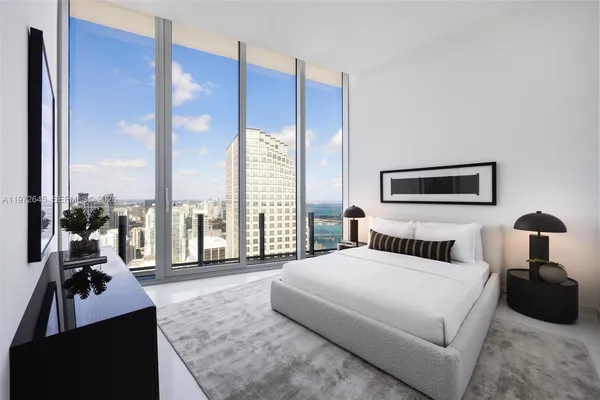 a bedroom with a bed and large windows