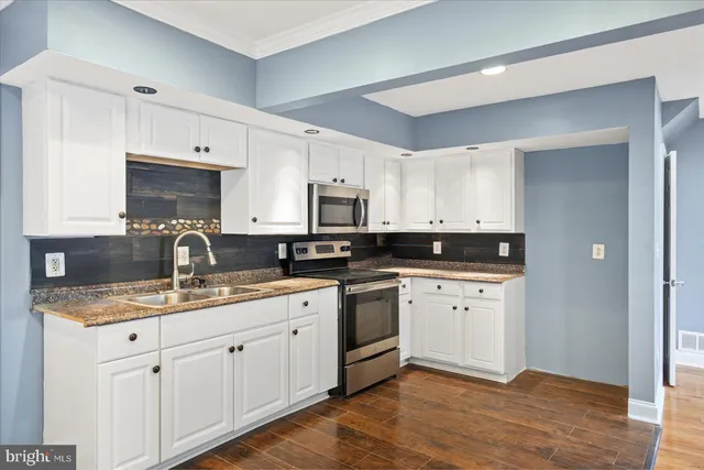 a kitchen with granite countertop white cabinets sink and stainless steel appliances