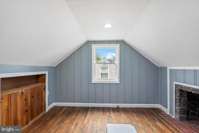 an empty room with wooden floor fireplace and windows