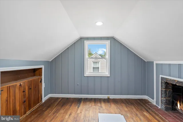 an empty room with wooden floor fireplace and windows