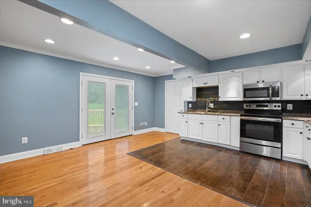 a large white kitchen with granite countertop a stove a sink and dishwasher with wooden floor