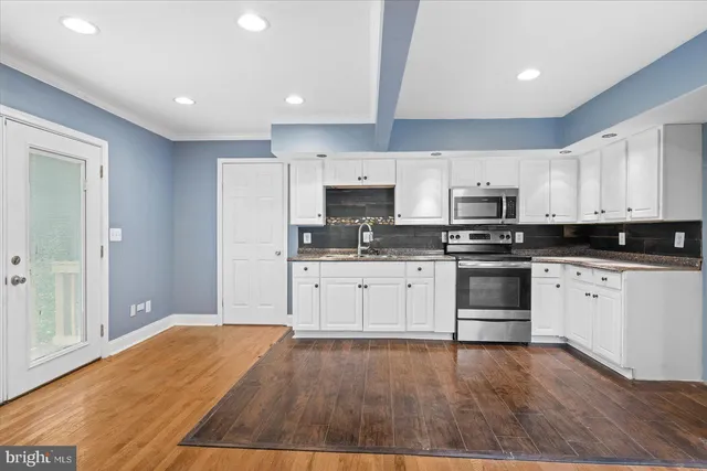 a kitchen with granite countertop white cabinets and stainless steel appliances